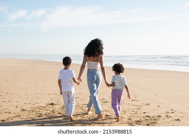 Back view of mother and children holding hands on beach. African American family spending time together on open air. Leisure, family time, togetherness concept - Powered by Shutterstock