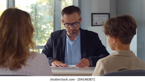 Back view of mother and son having interview with school headmaster. Mature male principal have meeting with schoolboy and parent in office - Shutterstock ID 2041483871