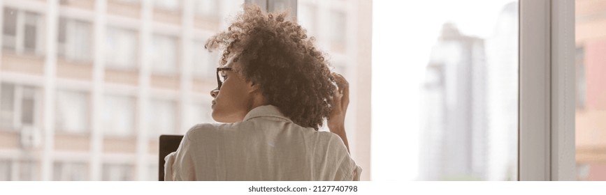 Back View Of Multiethnic Lady Sitting In Front Of The Window And Using Laptop In The Office. Copy Space