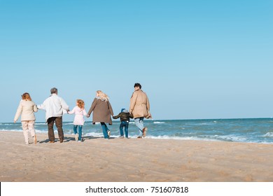 Back View Of Multigenerational Family Walking On Beach At Seashore