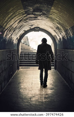 Back view of a mysterious man walking in a padestrian tunnel