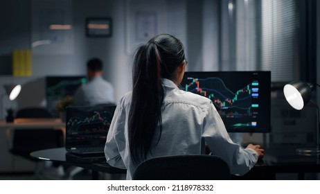 Back View Of Office Worker Analyze Graphs On Computer Screen. Female Trader Work And Monitor Stock Market In Office. 