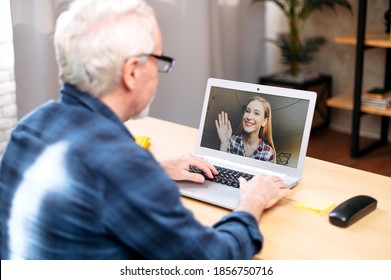 Back View Of An Older Man Is Using Laptop Computer For Video Connection While Sitting At Home. Video Call Concept