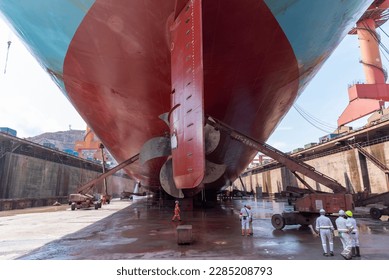 Back view on the container ship. Ship is inside a dry dock for routine maintenance and painting.