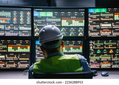 Back view on engineer operator and computer screens with modern following production system Industry 4.0 Head engineer of factory control process production line uses UI interfaces