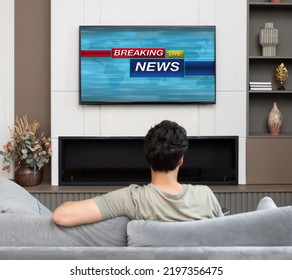 Back View On Excited Man Sitting On The Couch And Watching Breaking News On Tv At Home