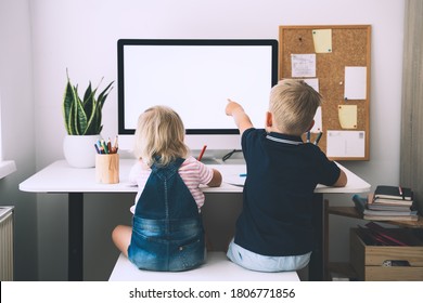 Back View On Little Preschool Boy And Girl Sitting At Working Desk With Computer With Blank White Screen At Home. Kids And Computer Technologies. Children Online Learning, Development Or Entertainment