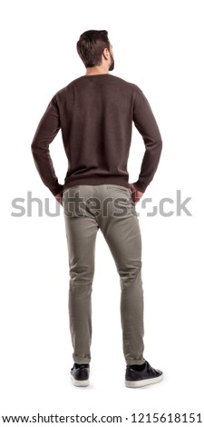 A back view on a modern fit and casually clothed man that stands in a relaxed posture and looks sideways. Man from back. Modern garb. Unrecognizable person.