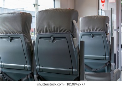 Back View On Passenger Railroad Train Seats. Empty Grey Interior Of Urban Express. New Plastic Seat Cover In Gray. City Public Transportation Inside. Row Of Comfortable Tourist Armchairs With Armrests