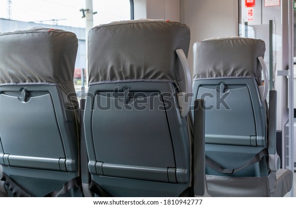 Back view on passenger railroad train seats.\
Empty grey interior of urban express. New plastic seat cover in\
gray. City public transportation inside. Row of comfortable tourist\
armchairs with armrests