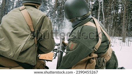 Back View On Re-enactors Dressed As American Infantry Soldiers Fire From Mortar. Usa Army Soldiers Of World War Ii. Mortar Shooting Explosions Forest. Reconstruction Defense Battles. Heroes Of War.