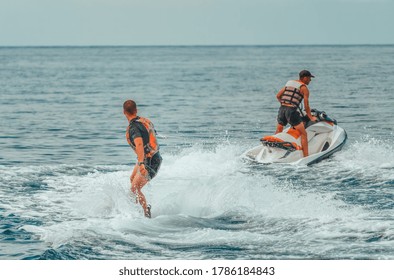 Back view on wakeboarder learn to ride on the sea in the summer sunny day. Wakeboarding on the beach. Copy space. The concept of an active and healthy life in harmony with nature.