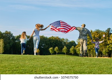 Back View, Patriotic Family Moving With Huge American Flag. People Running On The Grass.