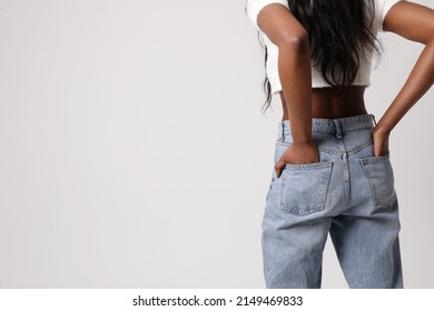 Back View Photo Of Black Woman Wear Blue Jeans And Top Isolated On Gray Wall.