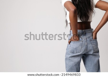 Back view photo of Black woman wear blue jeans and top isolated on gray wall.