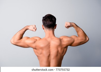 Back view photo of handsome confident man showing his muscular arms, isolated on grey background