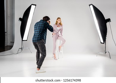 back view of photographer shooting beautiful young female model in photo studio 