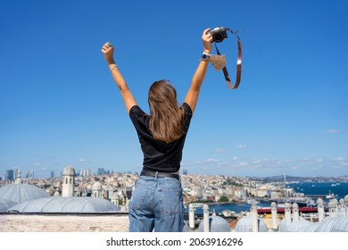 Back view of a photographer woman raising arms up towards the blue sky and Istanbul city view. - Shutterstock ID 2063916296