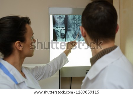Back view: picture of two doctors exploring spinal x-ray: lumbar and cervical region - first 2 cervical vertebrae (axis and atlas), coxofemural joint