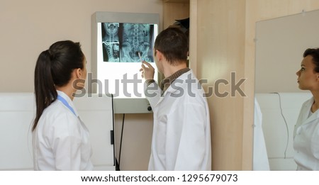 Back view: picture of two doctors exploring spinal x-ray: lumbar and cervical region - first 2 cervical vertebrae (axis and atlas), coxofemural joint