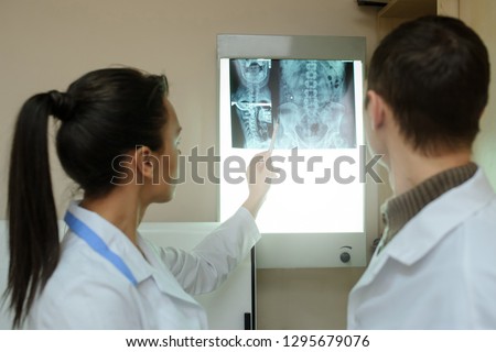 Back view: picture of two doctors exploring spinal x-ray: lumbar and cervical region - first 2 cervical vertebrae (axis and atlas), coxofemural joint