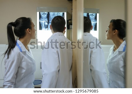 Back view: picture of two doctors exploring spinal x-ray: lumbar and cervical region - first 2 cervical vertebrae (axis and atlas), coxofemural joint
