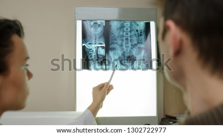 Back view: picture of two doctors exploring spinal x-ray: lumbar and cervical region - first 2 cervical vertebrae (axis and atlas), coxofemural joint