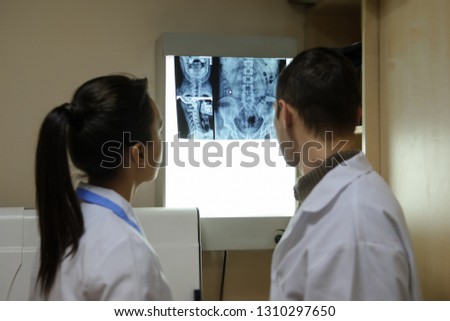 Back view: picture of two doctors exploring spinal x-ray: lumbar and cervical region - first 2 cervical vertebrae (axis and atlas), coxofemural joint