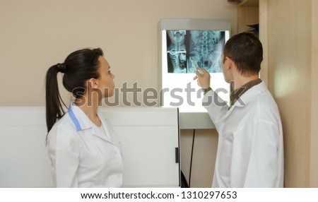 Back view: picture of two doctors exploring spinal x-ray: lumbar and cervical region - first 2 cervical vertebrae (axis and atlas), coxofemural joint