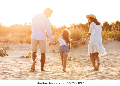 Back View Picture Of Young Happy Family Having Fun Together At The Beach.