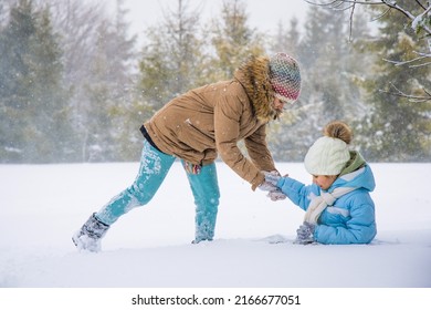 Back view of playful kids outerwear running, chasing in snowy spruce forest. Happy, cute female children playing catch, having fun outdoors in winter mountains. Concept of winter holidays.