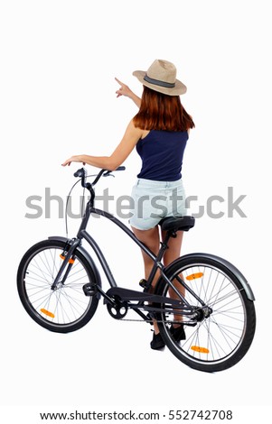 back view of pointing woman with a bicycle. cyclist sits on the bike. Rear view people collection.  backside view of person. Isolated over white background. Girl cyclist is leaning on a bicycle.