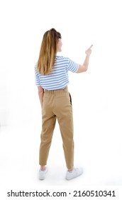 Back view of pointing young women in striped t-shirt. Young girl gestures. Rear view people collection, backside view of person. Isolated on white background. Studio shot. Full length.