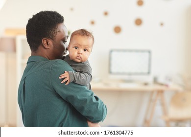 Back View Portrait Of African-American Man Holding Cute Mixed-race Baby Looking At Camera While Posing In Cozy Home Interior, Copy Space