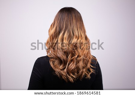 Back view portrait of beautiful curly dark blonde woman wearing black sweater. Degradé joelle effect, balayage similar