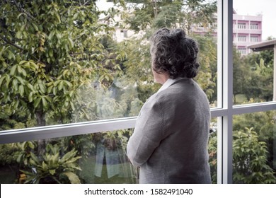 back view, Portrait of elderly Asian senior woman with grey hair looking out window for thinking seriously, lifestyle concept