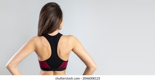 Back view portrait of a fitness woman on gray background