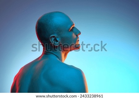 Back view portrait of handsome young bald man posing shirtless against blue studio background in neon light. Concept of male beauty, sportive and healthy lifestyle, body care