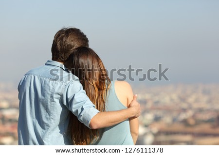 Back view portrait of a happy couple dating contemplating the city