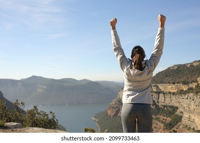 Back view portrait of a happy trekker raising arms in nature celebrating success - Shutterstock ID 2099733463