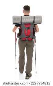 Back view portrait of hiker with a backpack and trekking poles isolated on white background. Thirty years old man posing in studio. - Shutterstock ID 2297934815