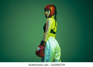 Back view. Portrait of professional female boxer in sports protective equipment posing isolated on green background in neon. Sport, competition, hobby, results, success concept. - Powered by Shutterstock