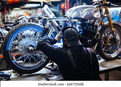 Back view portrait of tattooed man wearing protective mask welding motorcycle frame in workshop - Powered by Shutterstock