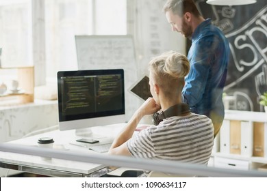 Back view portrait of two contemporary young men in casual wear coding using computer collaborating  on business project in modern office, copy space
