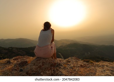 Back view portrait of a woman alone contemplating sunset in the mountain - Shutterstock ID 2047842083