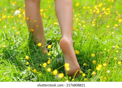 Back view portrait of a woman bare feet walking on the grass