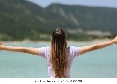 Back view portrait of a woman outstretching arms in nature - Shutterstock ID 2280493139