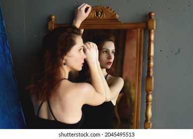 Back view portrait of young beautiful woman near the mirror and looking aside.