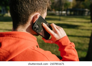 Back View Portrait Of A Young Man Talking Phone. Оver The Shoulder Young Man Calling On The Black Mobile Phone On The Street. Close-up Behind The Back. The Man Lowered His Head. Selective Focus.
