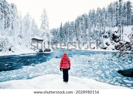 Back view of pre-teen girl enjoying breathtaking view of winter landscape in Oulanka National Park in Lapland Finland